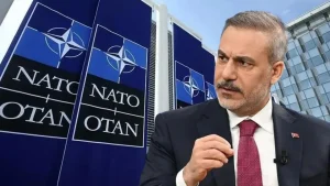 Хакан Фідан на саміті НАТО перед банерами альянсу