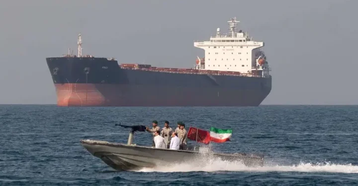 Иранский катер с флагом возле нефтяного танкера в Ормузском проливе