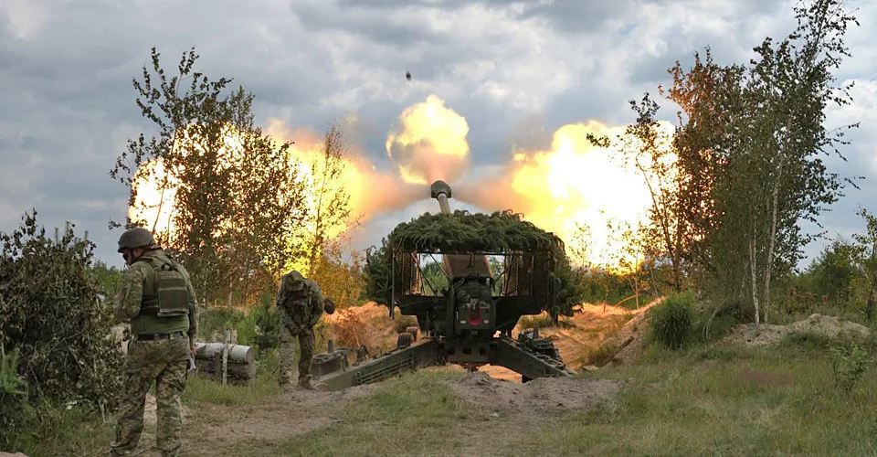 Прикордонники біля замаскованої артилерійської установки під час пострілу серед дерев
