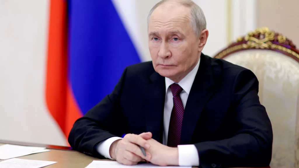 Володимир Путін сидить за столом на тлі російського прапора