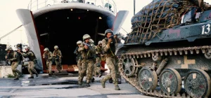 Морські піхотинці з гвинтівками вибігають з десантного корабля біля танка