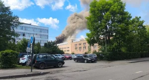 Густий дим над будівлями та парковкою з автомобілями під синім небом