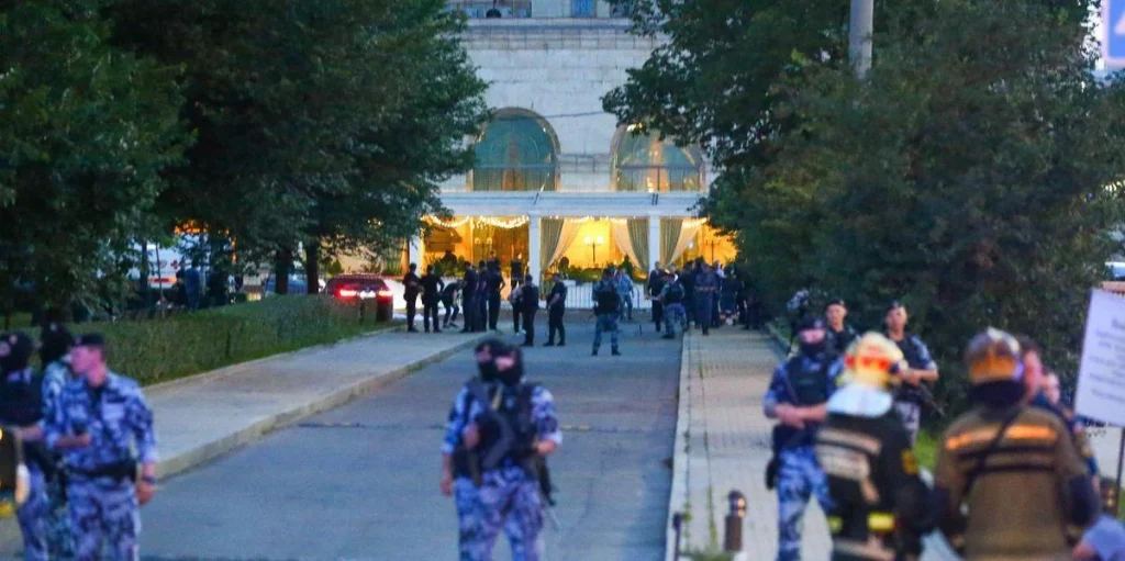 Поліцейські в камуфляжі з автоматами на алеї біля освітленого ресторану в сутінках