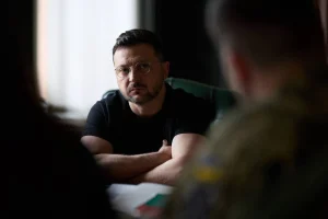 Володимир Зеленський у чорній футболці сидить зі схрещеними руками в зеленому кріслі