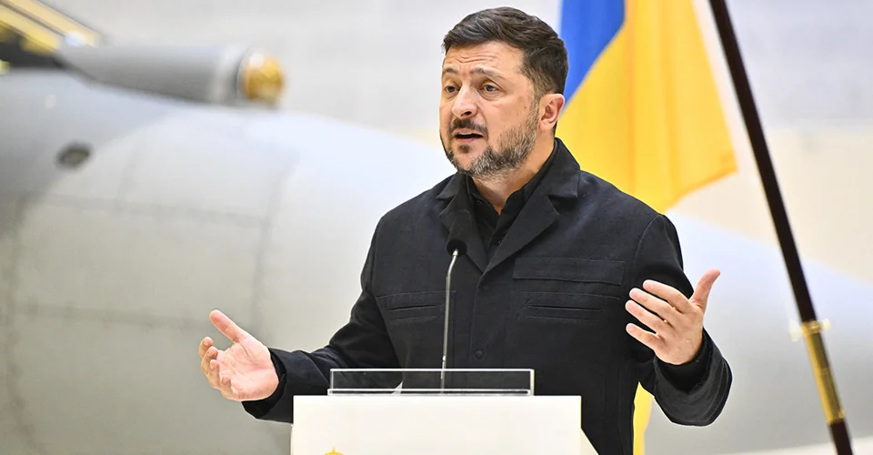 Президент Зеленський виступає за трибуною на тлі українського прапора та літака