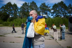 Звільнений військовий з українським прапором на плечах емоційно цілує тканину